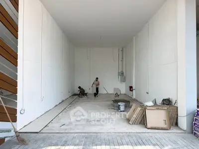 Spacious unfinished garage or storage area with high ceiling and construction materials.