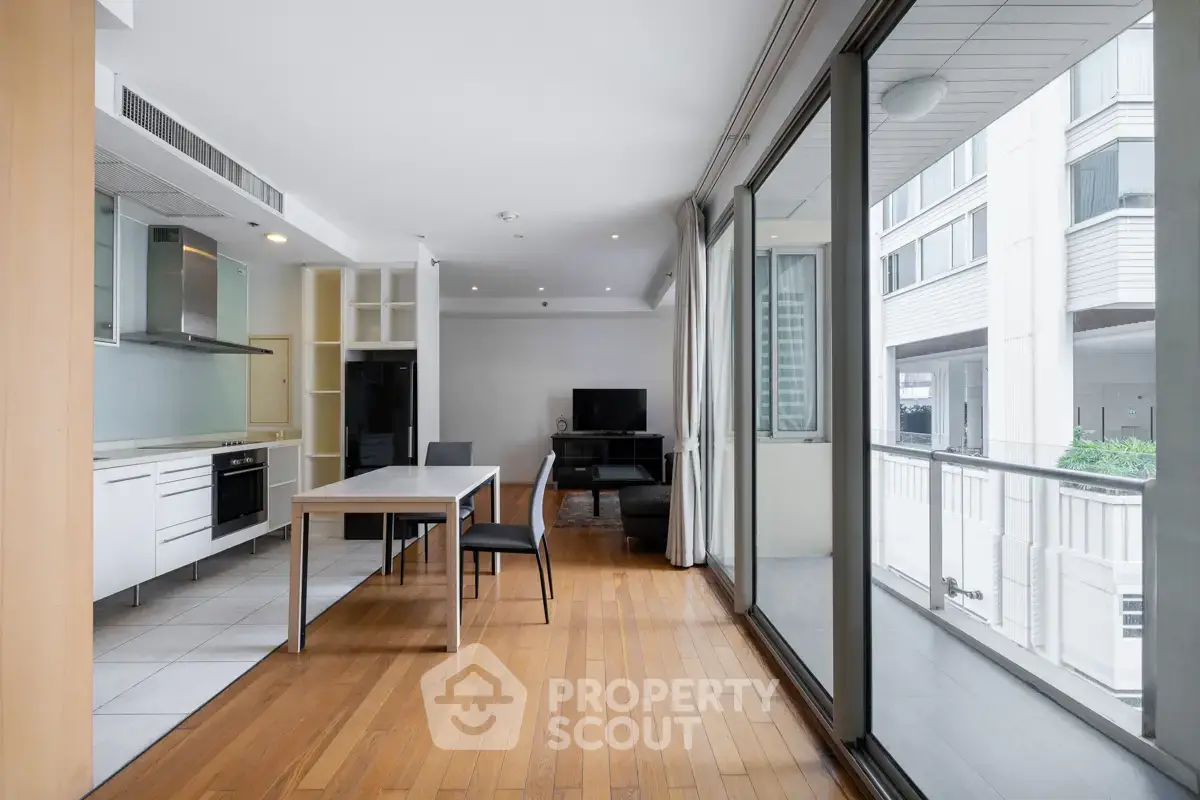 Spacious modern living room with open kitchen and balcony view in urban apartment.