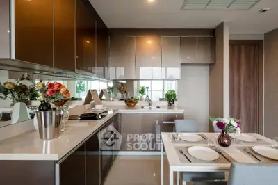 Modern kitchen with sleek cabinetry and dining area, featuring elegant decor and natural lighting.