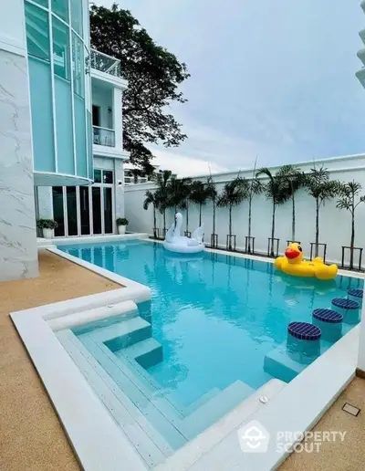 Luxurious modern home with stunning private pool and playful inflatables, perfect for relaxation and entertainment.