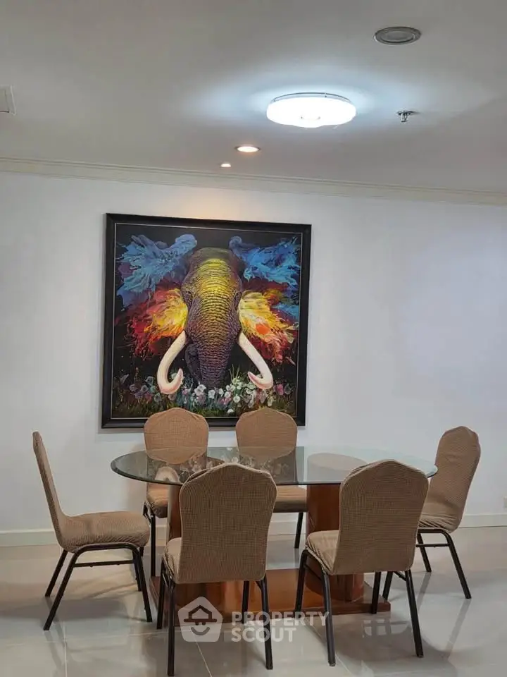 Elegant dining area with glass table and vibrant elephant artwork, perfect for modern living.
