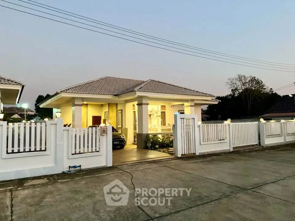 Charming single-story home with spacious driveway and modern fence at sunset.