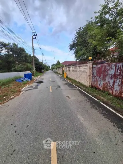 Charming suburban street view with lush greenery and rustic fences, perfect for serene living.