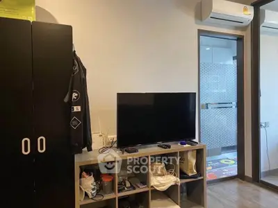 Modern living room with TV and storage unit, adjacent to a bathroom.