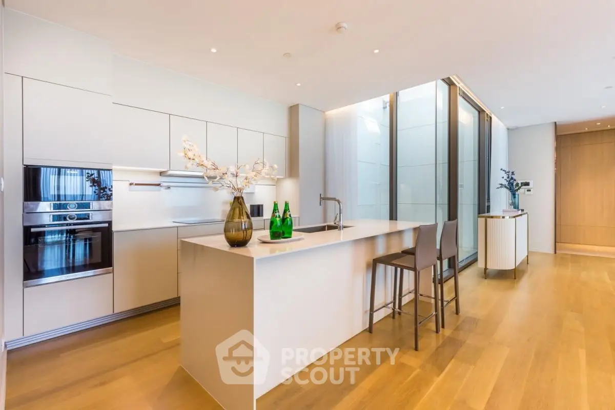 Modern kitchen with sleek design, island seating, and built-in appliances in luxury apartment.