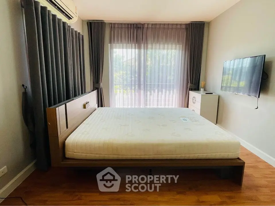 Spacious bedroom with modern decor and large window for natural light.