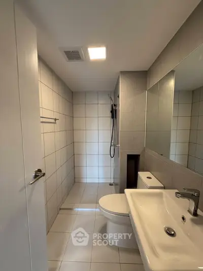 Modern bathroom with sleek fixtures and tiled walls, featuring a spacious shower area.