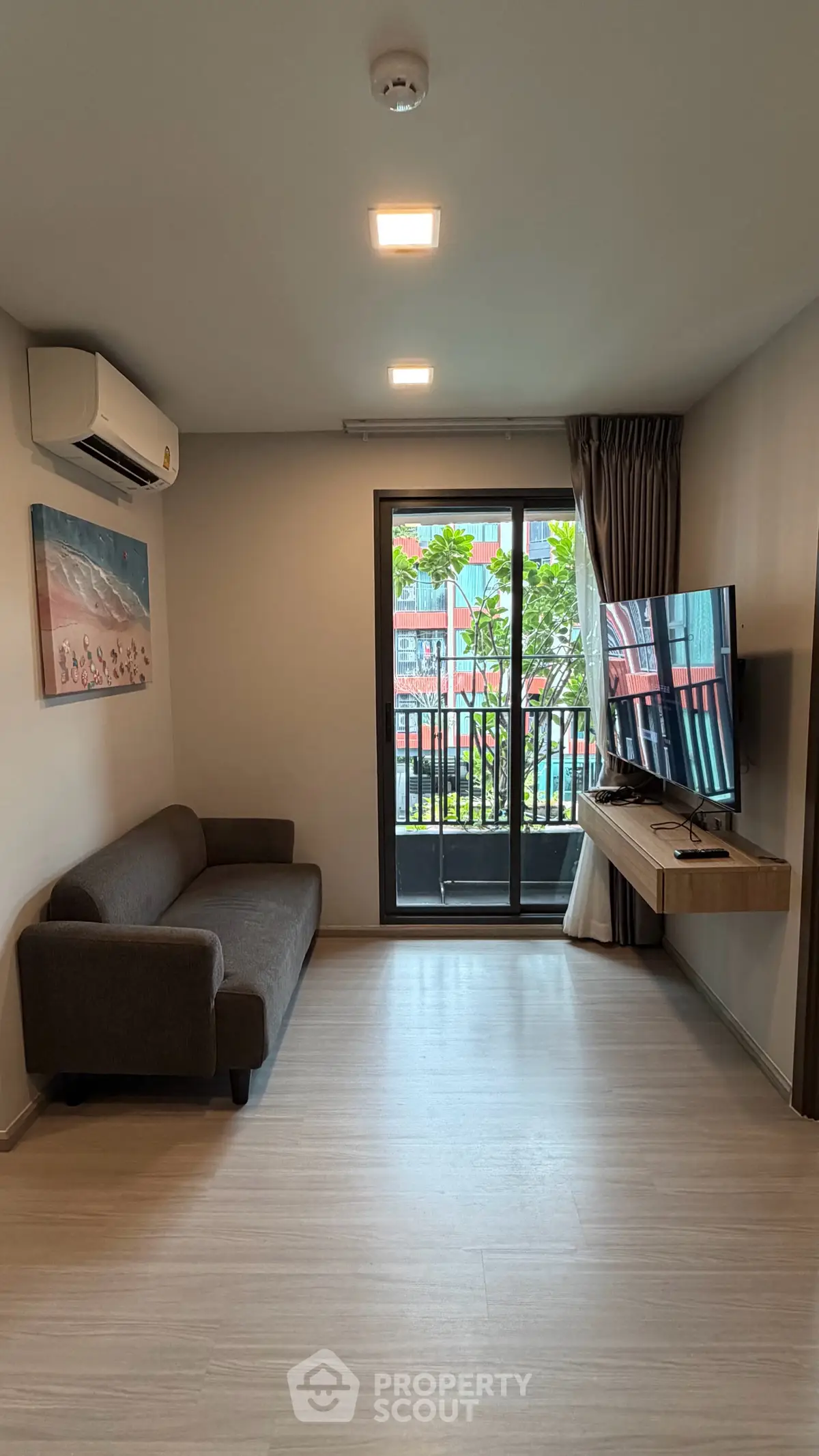 Modern living room with sleek sofa, wall-mounted TV, and balcony access in stylish apartment.