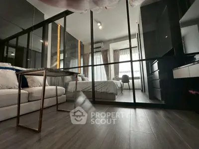 Modern bedroom with glass partition and cozy seating area, featuring sleek design and ample natural light.