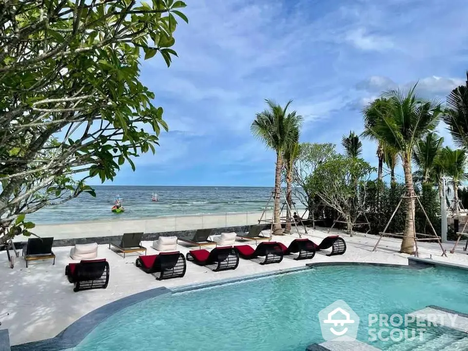 Luxurious beachfront pool with stunning ocean view and palm trees, perfect for relaxation and leisure.