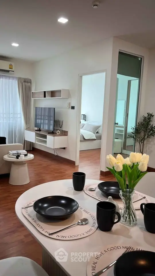 Modern open-plan living room with dining area and bedroom view, featuring stylish decor and natural light.