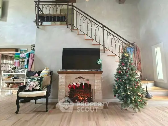 Charming living room with festive decor, cozy fireplace, and elegant staircase, perfect for holiday gatherings.