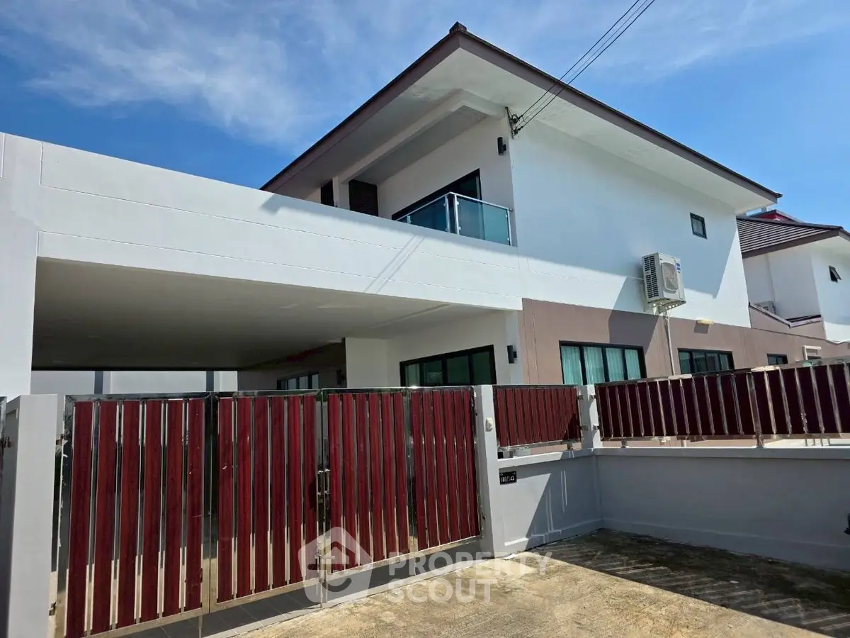Modern two-story house with sleek design and spacious driveway under clear blue sky.