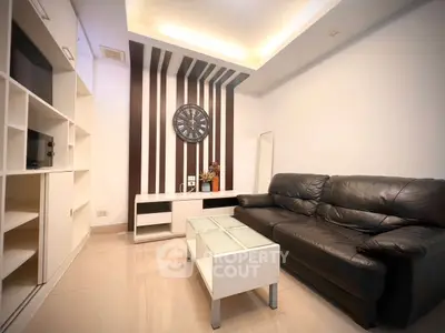 Modern living room with sleek black leather sofa and stylish wall clock