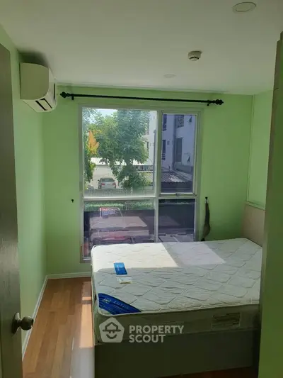 Cozy bedroom with large window and green walls, featuring a comfortable bed and air conditioning.