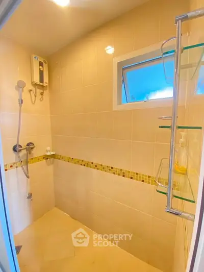 Modern bathroom with shower and glass shelves in a bright, tiled interior.