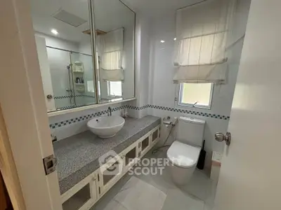 Modern bathroom with elegant fixtures and large mirror, featuring a sleek countertop and stylish basin.