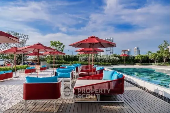 Luxurious poolside area with red umbrellas and modern seating, perfect for relaxation and leisure.