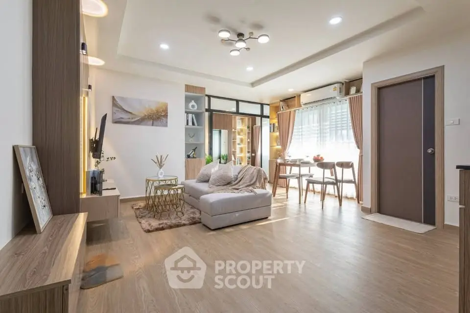 Modern living room with stylish decor and open dining area, featuring elegant lighting and wooden flooring.