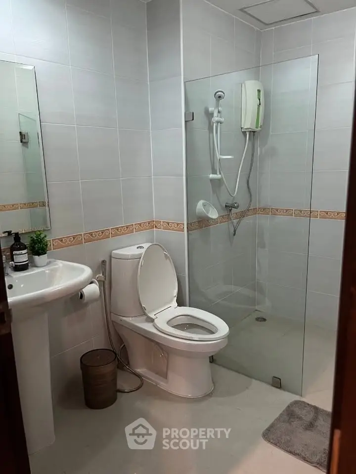 Modern bathroom with glass shower and sleek fixtures in contemporary apartment.