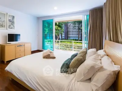 Spacious bedroom with modern decor and garden view balcony access.
