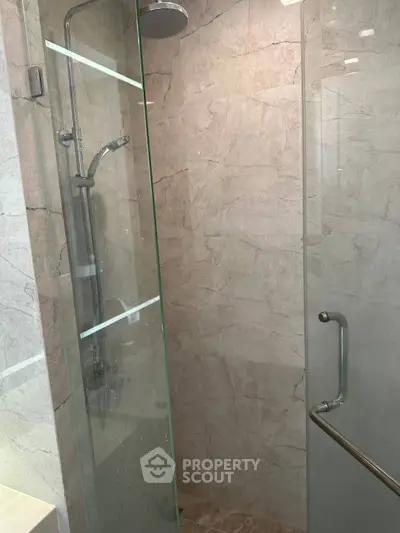 Modern bathroom with glass shower enclosure and sleek marble tiles.