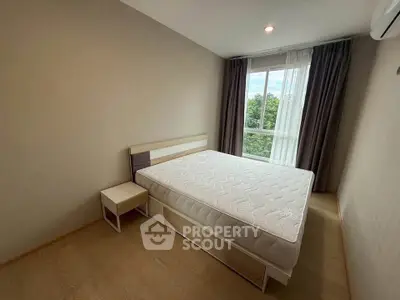 Cozy bedroom with large window and natural light in modern apartment.