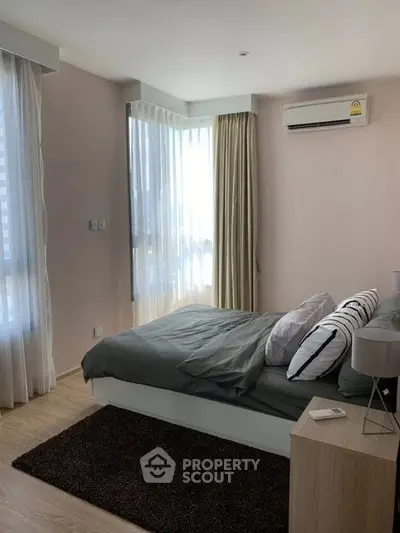 Modern bedroom with large windows and air conditioning, featuring stylish decor and natural light.