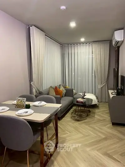 Modern living room with stylish decor and dining area, featuring herringbone flooring and elegant curtains.