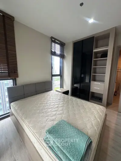 Modern bedroom with large window and built-in wardrobe in urban apartment
