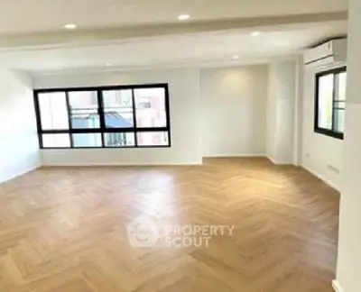 Spacious modern living room with large windows and elegant wooden flooring.