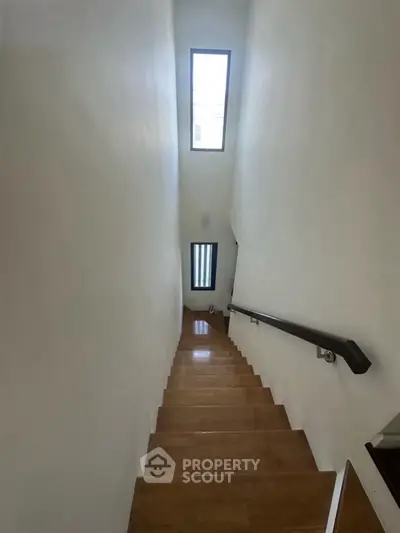 Modern staircase with wooden steps and skylight in a minimalist home