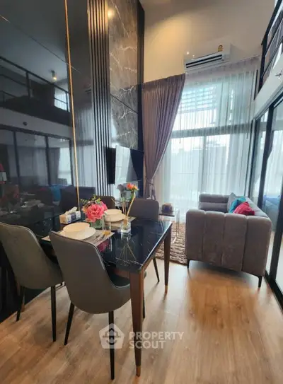 Modern living room with high ceilings, elegant dining area, and floor-to-ceiling windows.