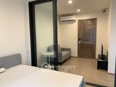 Modern apartment interior with bedroom and living area, featuring sleek design and air conditioning.