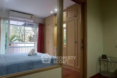Cozy bedroom with large window and balcony view, featuring built-in wardrobes and air conditioning.
