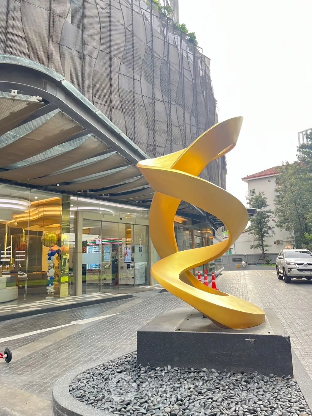 Modern building entrance with unique golden sculpture and sleek architecture.