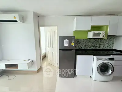 Modern apartment kitchen with washing machine and fridge, open layout design.