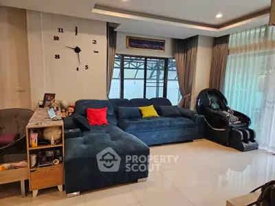 Spacious living room with modern blue sectional sofa and massage chair, perfect for relaxation.