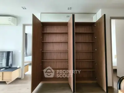 Spacious modern living room with open wooden storage cabinets and sleek design.