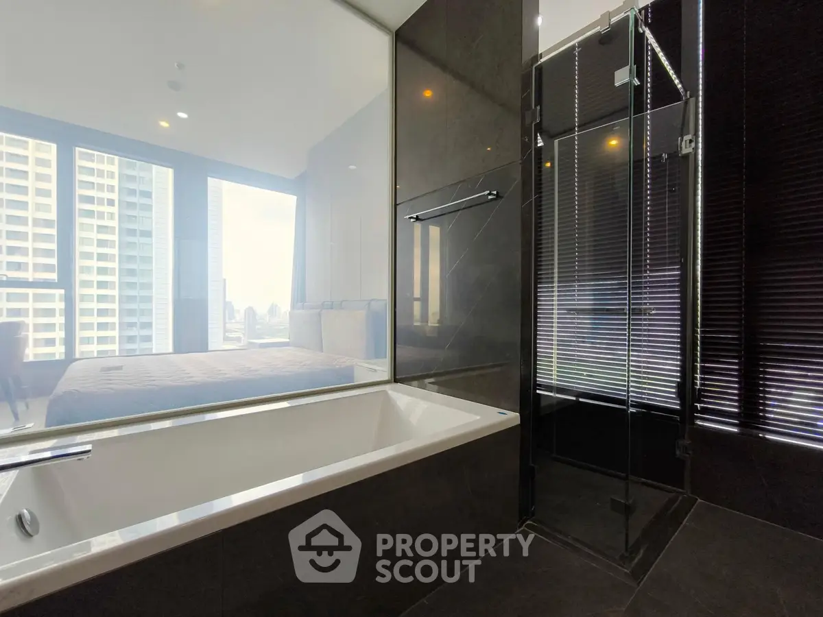 Luxurious modern bathroom with glass shower and city view from large window.