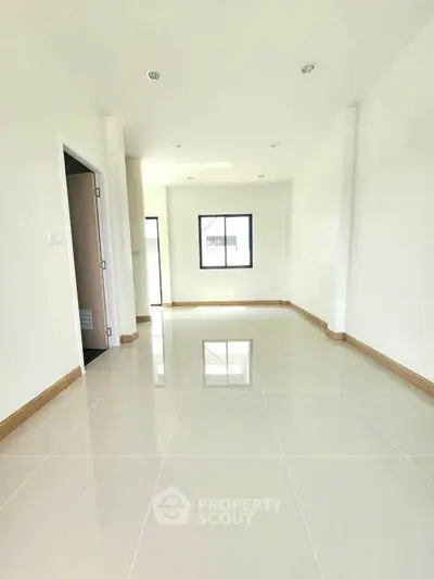 Spacious empty room with glossy tiled floor and large windows, perfect for customization.