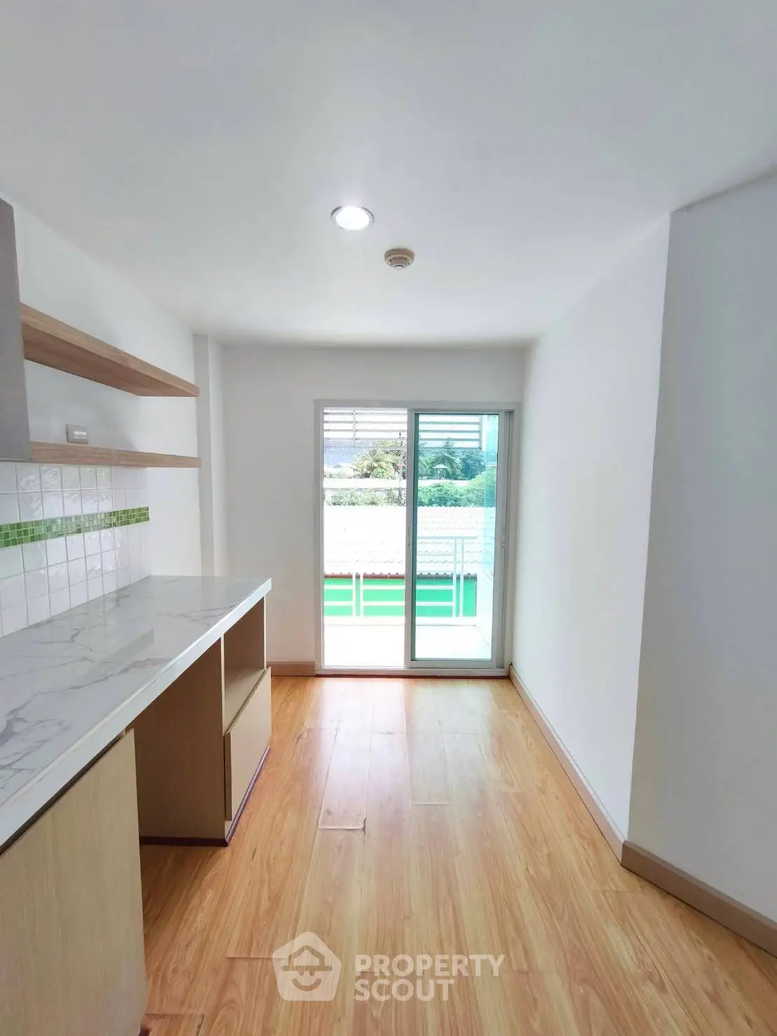 Bright kitchen with wooden flooring and sliding glass doors leading to balcony.