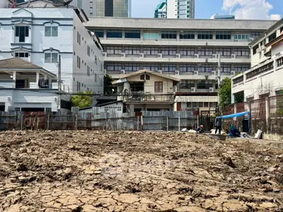 Urban land plot ready for development with city buildings in the background.