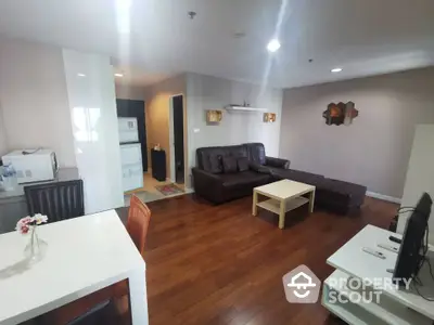 Spacious living room with modern decor and wooden flooring in a cozy apartment.