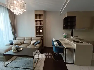 Luxurious modern living room with elegant chandelier and open kitchen layout.