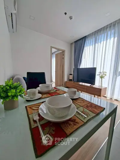 Modern living room with dining area, TV, and large window with curtains.