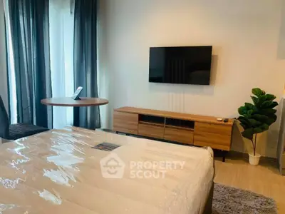 Modern bedroom with sleek TV setup and stylish furniture in a cozy apartment.