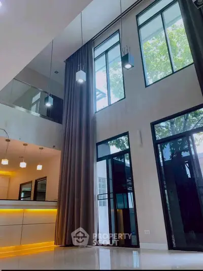 Stunning modern living room with high ceilings and large windows, featuring elegant lighting and sleek design.