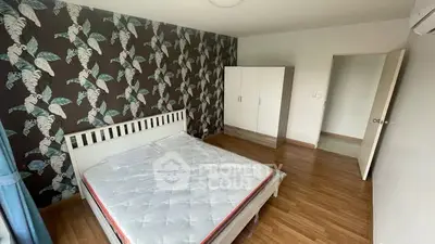 Spacious bedroom with stylish wallpaper and wooden flooring