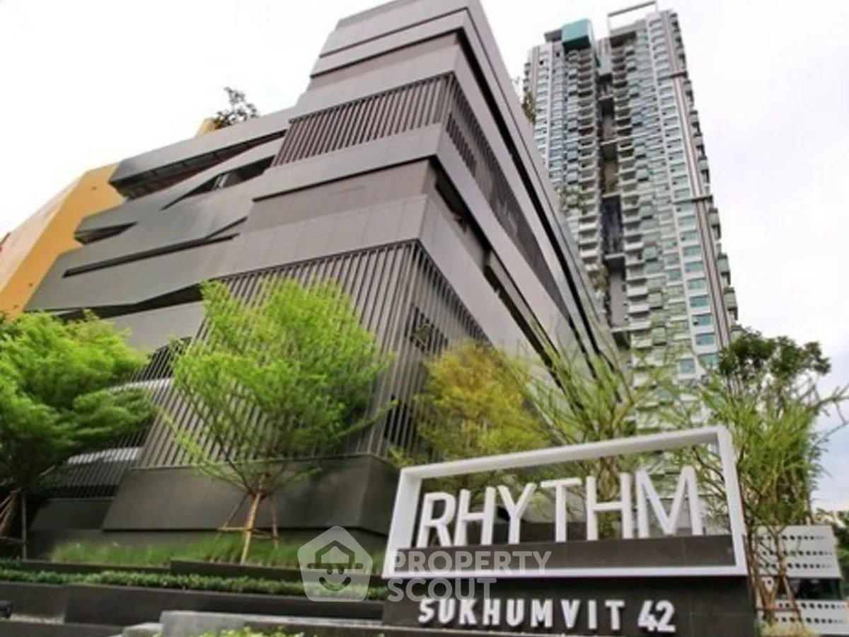 Modern high-rise building with sleek design at Rhythm Sukhumvit 42, featuring lush greenery and urban elegance.
